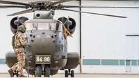 Soldier crossing in front of a transport helicopter.