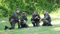 4 Soldaten sitzen auf einer Wiese