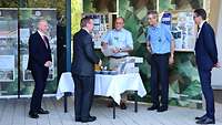 Mehrere Männer an einem improvisierten Stand mit Kostproben und Kartons