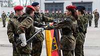 Feierliches Gelöbnis mit angetretenen Soldatinnen und Soldaten die eine Flagge halten
