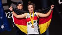 Eine Sportlerin mit Bronzemedaille und Deutschlandflagge