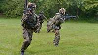 Vier Soldaten bewegen sich auf einem Feld und haben ein Gewehr von Typ G36 in ihren Händen