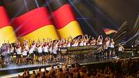 Team Deutschland auf der Bühne in der Merkur-Spiel-Arena. Alle winken dem Publikum zu.