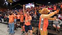 Niederlänische Fans jubeln und tanzen im Publikum auf und vor einer Tribüne in einer Sportarena