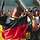 Ein deutscher Athlet jubelt mit Deutschlandflagge und wird von Fans beklatscht.