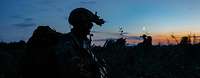 Silhouette eines Soldaten mit Helm, Nachsichtgerät und Rucksack auf dem Rücken in der Abenddämmerung