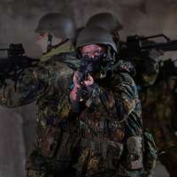 Drei Soldaten stehen sich mit dem Rücken gegenüber und halten jeweils ein G36 im Anschlag.
