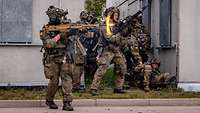 Eine Gruppe Soldaten steht im Feuergefecht. An der Mündung einer Waffe entsteht ein Feuerstrahl.