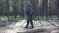 Ein Soldat sucht den Boden mit einem Metalldetektor ab.
