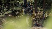 Ein Soldat steht am Waldrand und richtet eine Panzerfaust nach vorn.