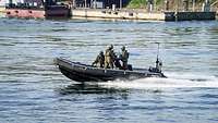 Ein Speedboot mit drei Soldaten fährt über Wasser