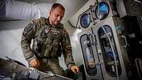 Ein Soldat steht in einem weißen Zelt am Fließband einer Maschine.