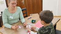 Eine Frau spielt ein Kartenspiel mit einem Jungen. 