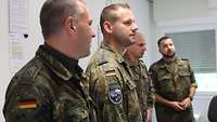 Vier Soldaten stehen in einem Raum und unterhalten sich. 