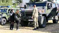 Zwei Frauen schauen sich ein Militärfahrzeug an.