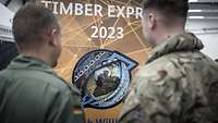 Zwei Soldaten vor einem Banner mit dem Patch zu TIMBER EXPRESS.
