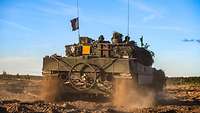 Ein Kampfpanzer von hinten fährt davon.