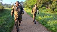 Marsch Drei Soldaten marschieren schnell einen Weg entlang.
