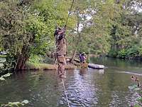 Doppelter Seilsteg Ein Soldat steht auf einem Stahlseil und hält sich an einem anderen fest. Unter ihm das Wasser.
