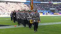 Ein Ehrenzug des Wachbataillons im Duisburger Stadion vor vollen Rängen.