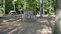 Ein Waldspielplatz für Kinder, im Vordergrund steht ein Klettergerüst aus Holz.