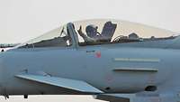 Pilot eines Kampfjets mit Hand zum Gruß an der Stirn 