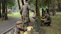 Vier Soldaten der Führungsakademie und des Bundeswehrkrankenhauses säubern Grabsteine auf einem Friedhof