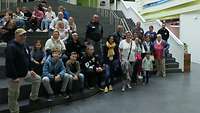 Eine Personengruppe steht und sitzt auf einer Treppe und posiert für ein Gruppenbild.