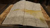 Zwei handschriftliche Seiten eines Heftes, darauf sieht man eine Landschaftsskizze.