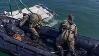 Wasserbergung Zwei Personen auf einem Schlauchboot befestigen Seile an einer Plattform im Wasser.