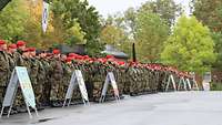 Soldatinnen und Soldaten stehen neben Aufstellern mit den Abzeichen ihrer Verbände in Formation angetreten.