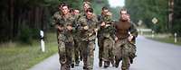 Eine Gruppe von Soldaten rennen auf einer asphaltierten Straße.