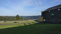 Ein Gebäude steht auf einer Wiese und der Ausblick geht in den Nationalpark Eifel. 