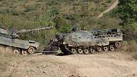 Der Bergepanzer zieht den Kampfpanzer aus der freien Fläche.