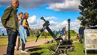 Mehrere Personen schauen sich bei einer Vorführung einen Minennräumroboter an.