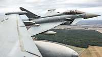 Zwei Eurofighter fliegen dicht nebeneinander über eine Landschaft