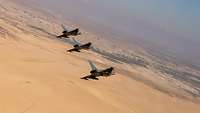 Drei Eurofighter fliegen nebeneinander weg von der Kamera. Im Hintergrund sieht man die jordanische Landschaft und Wüste.