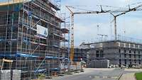 Eine Baustelle, mehrere Gebäude sind kurz vor dem Richtfest