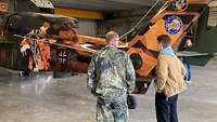 Menschen stehen vor einem folierten Hubschrauber in einer Halle