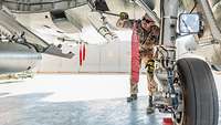 Ein Soldat schraubt an einem Eurofighter.