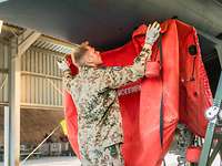 Ein Soldat in Nahaufnahme steht vor einem Eurofighter und nimmt die roten Schutzabdeckung von den großen Lufteinlässen ab.