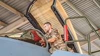 Nahaufnahme eines Eurofightercockpits im Shelter. Ein Soldat nimmt rote Abdeckungen ab und kontrolliert das Cockpit. 