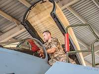 Nahaufnahme eines Eurofightercockpits im Shelter. Ein Soldat nimmt rote Abdeckungen ab und kontrolliert das Cockpit. 