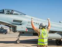 Ein Soldat steht neben einem Eurofighter und gibt dem Piloten im Cockpit Handzeichen. Seine beiden Arme zeigen nach oben.