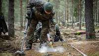 Ein Soldat scannt den Boden mit einer Handsonde.