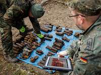 Zwei Soldaten mit Tablett dokumentieren die gefundene Munition.