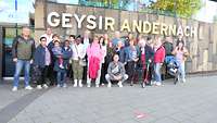 Mehrere Personen stehen vor einem Gebäude mit der Aufschrift „Geysir Andernach“.
