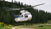 A helicopter is hovering in the air above a meadow.