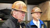 Two men are wearing safety helmets on their heads.