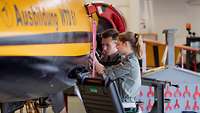 A young woman and a young man working together on an aircraft.